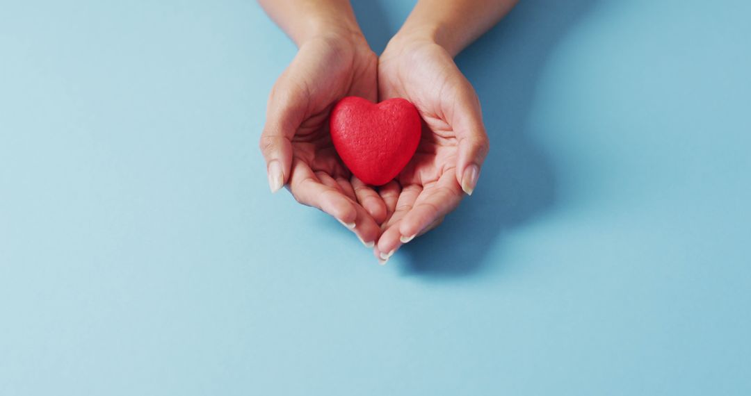 Image of hands of caucasian woman holding heart on blue background - Free Images, Stock Photos and Pictures on Pikwizard.com