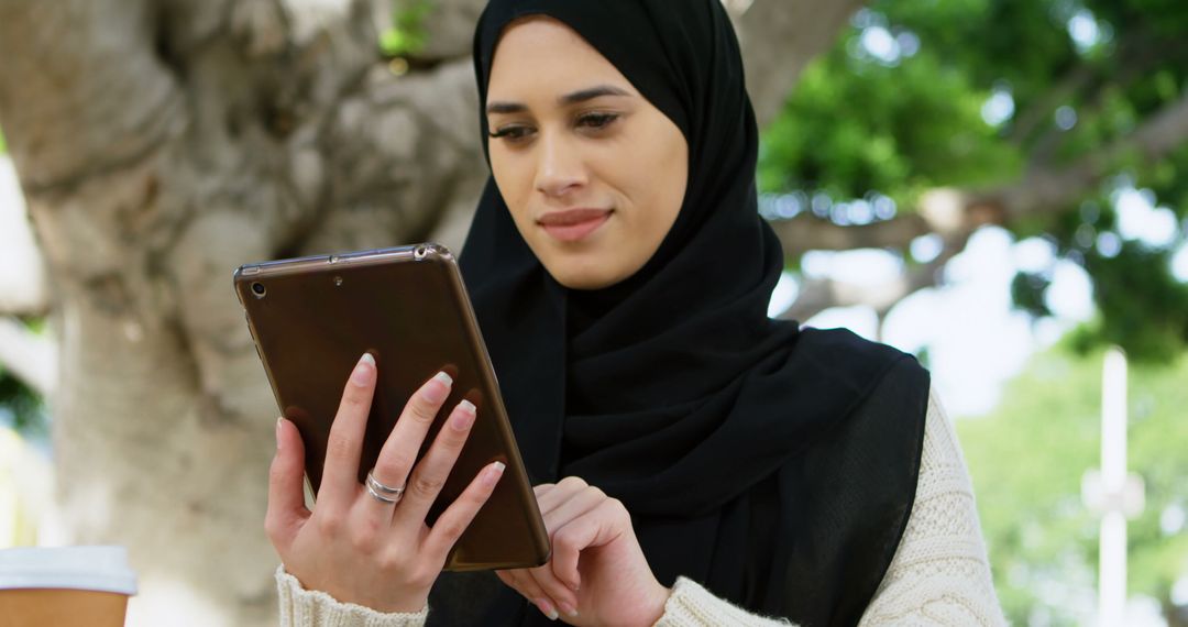 Muslim Woman Using Digital Tablet in Park - Free Images, Stock Photos and Pictures on Pikwizard.com