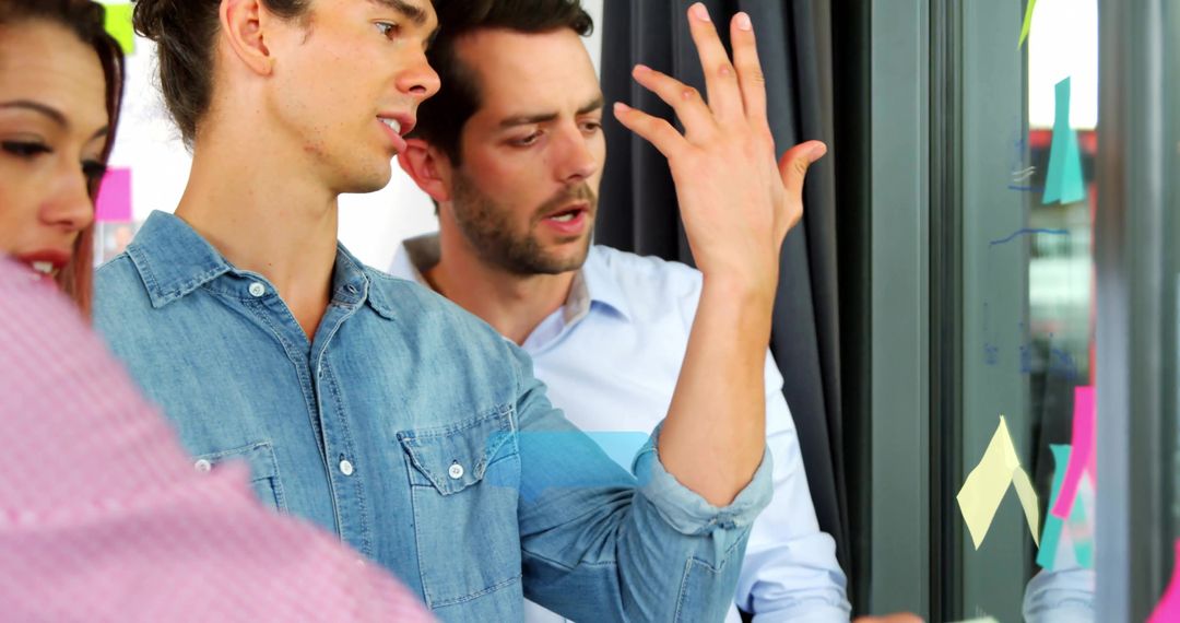 Focused Team Collaborating with Glass Note Board