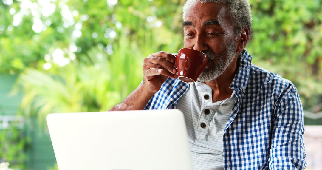 Elderly Man Drinking Coffee While Using Laptop Outside in Green Garden - Free Images, Stock Photos and Pictures on Pikwizard.com