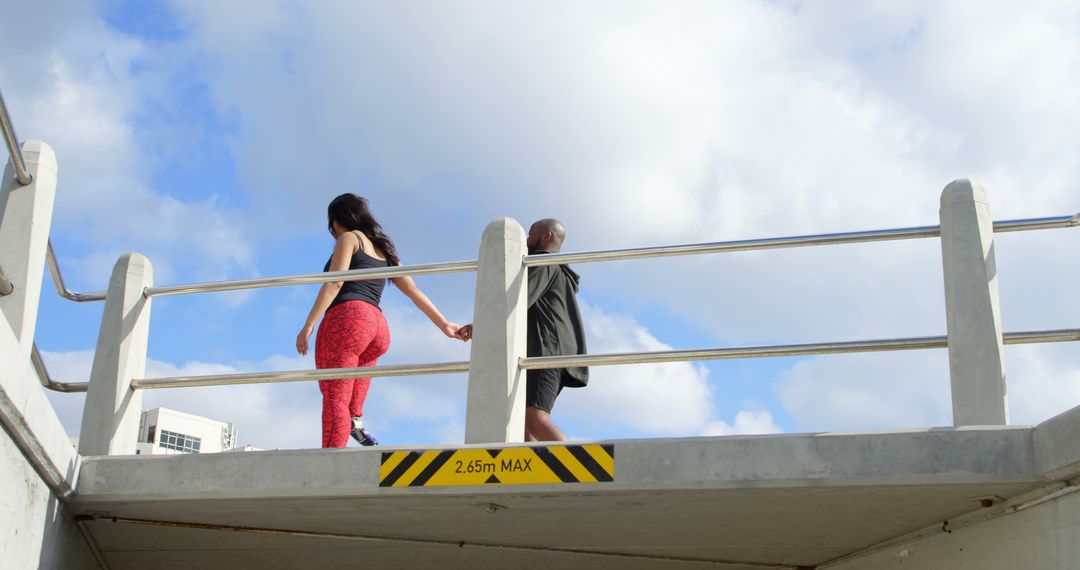 Couple Walking on Bridge Hand in Hand Against Blue Sky - Free Images, Stock Photos and Pictures on Pikwizard.com