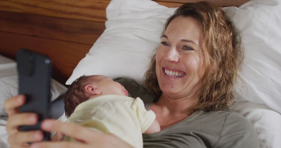 Smiling Mother Holding Newborn Baby and Taking a Selfie - Free Images, Stock Photos and Pictures on Pikwizard.com