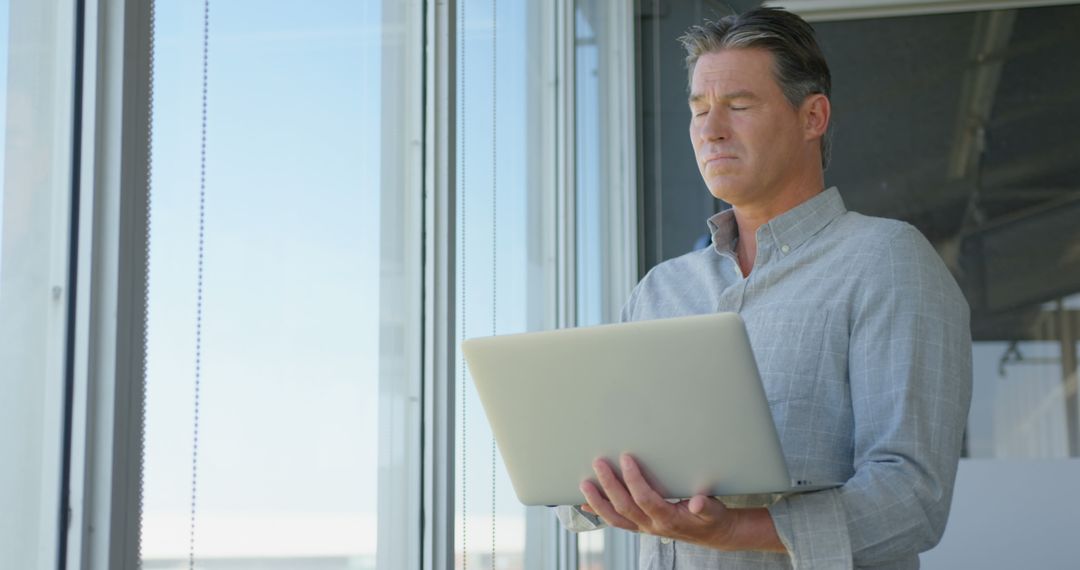 Focused Executive Using Laptop in Modern Office Environment