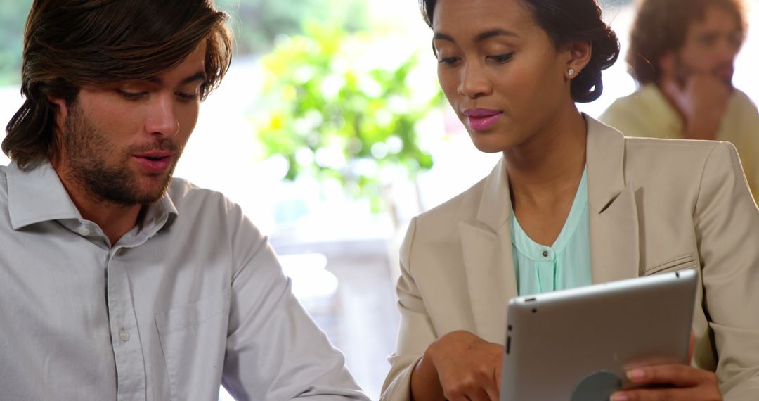 Business Professionals Discussing Work Over Tablet in Cafe