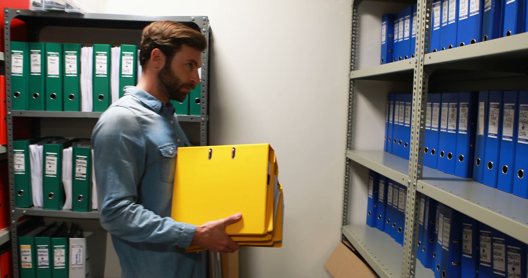 Man organizing files in office archive room - Free Images, Stock Photos and Pictures on Pikwizard.com