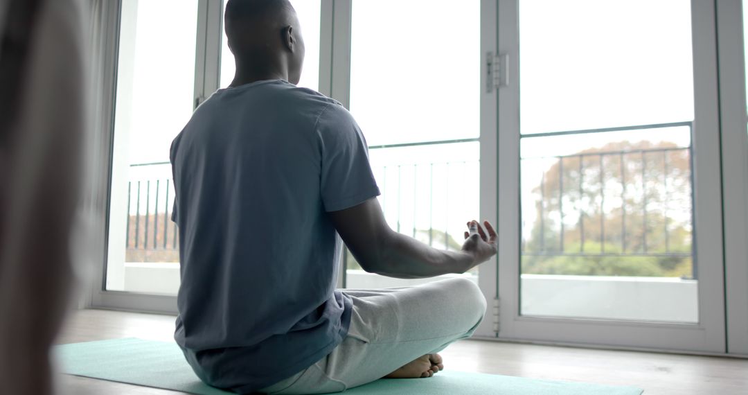 Man Practicing Yoga Meditation at Home Front of Window - Free Images, Stock Photos and Pictures on Pikwizard.com