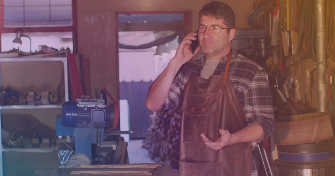 Caucasian Male Worker in Rustic Workshop Communicating on Smartphone