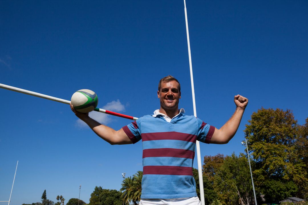 Portrait of happy rugby player holding ball against blue sky - Free Images, Stock Photos and Pictures on Pikwizard.com