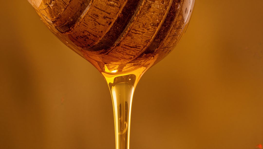 Dripping Golden Honey from Wooden Dipper Highlighting Rich Texture
