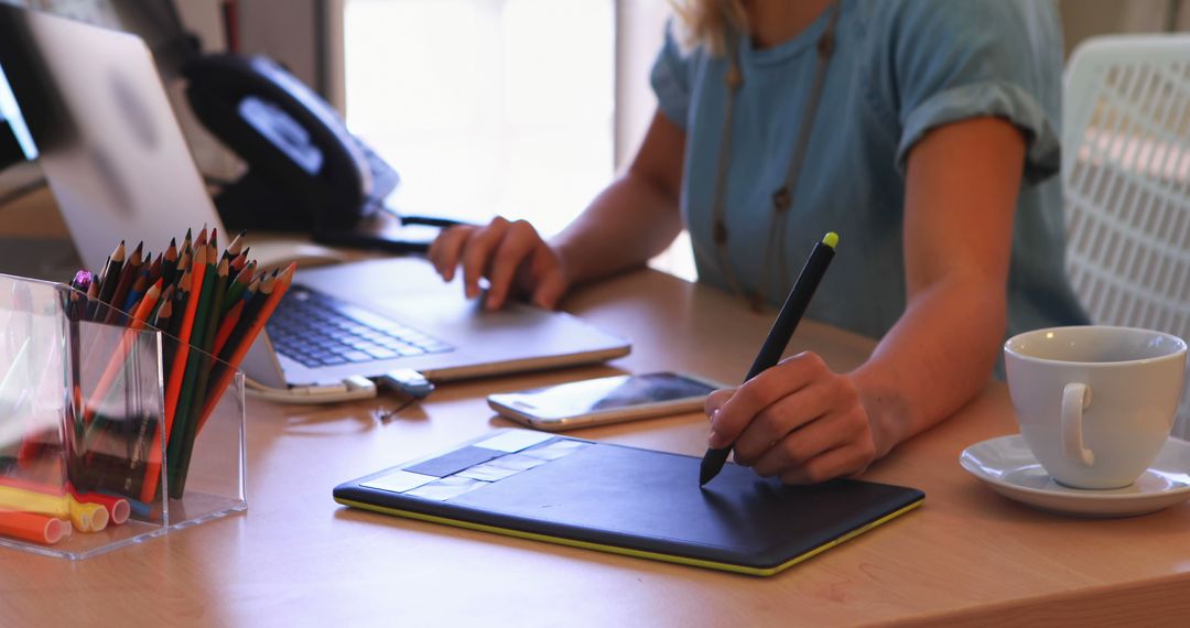 Designer Using Digital Tablet in Creative Workspace with Modern Tools