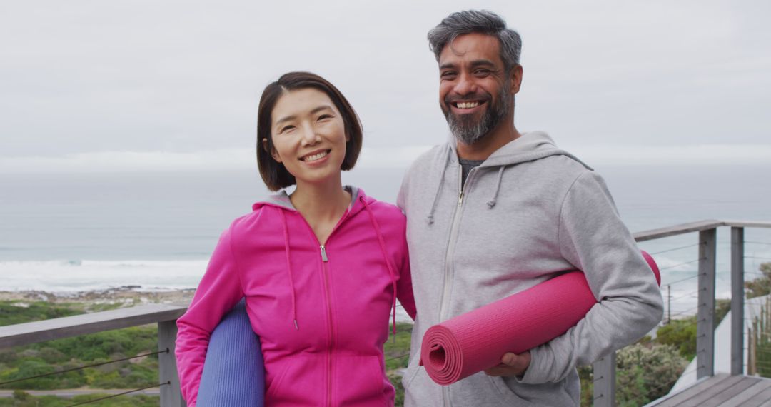 Diverse Couple with Yoga Mats Smiling on Balcony