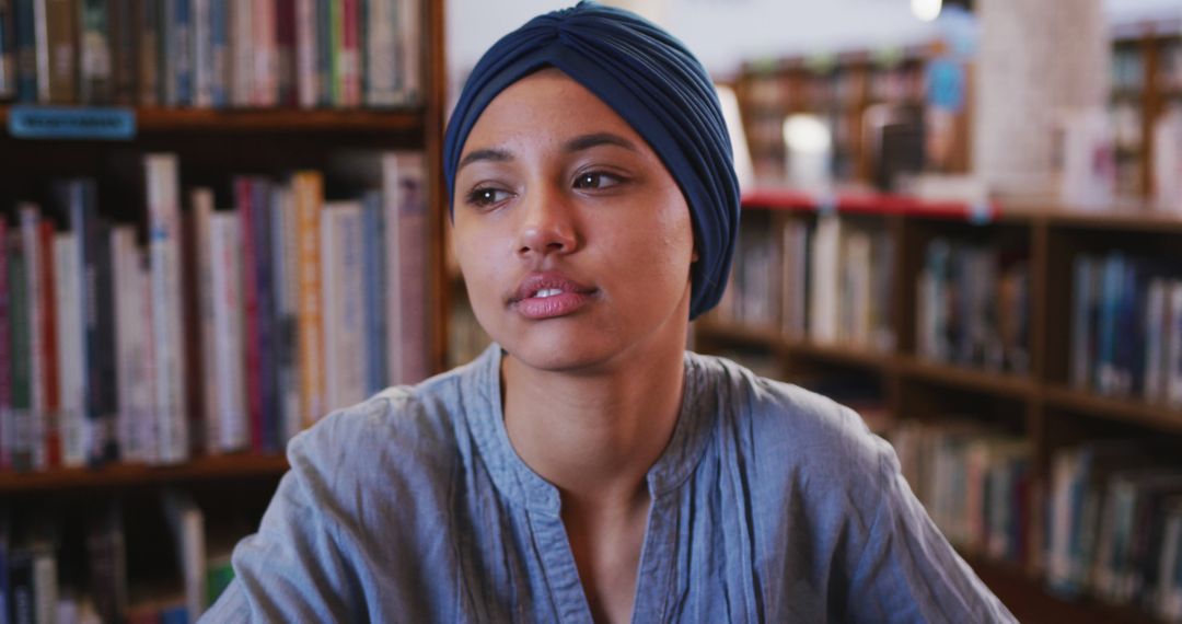 Thoughtful Young Woman in Library Wearing Headscarf - Free Images, Stock Photos and Pictures on Pikwizard.com