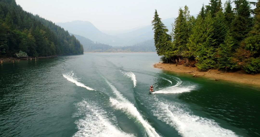 Person Water Skiing on Mountain Lake with Forested Shores - Free Images, Stock Photos and Pictures on Pikwizard.com