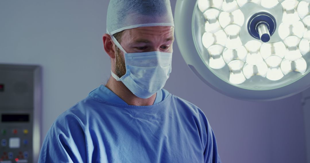 Caucasian male surgeon wearing face mask during surgery in operating room - Free Images, Stock Photos and Pictures on Pikwizard.com