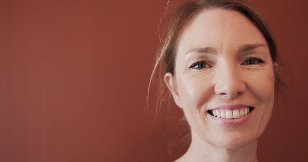 Smiling Woman with Brown Hair Facing Camera against Red Background - Free Images, Stock Photos and Pictures on Pikwizard.com