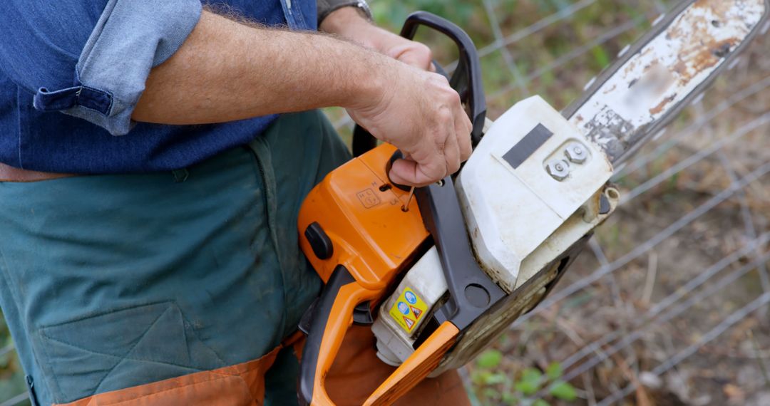 Middle-Aged Worker Preparing Chainsaw for Outdoor Task - Free Images, Stock Photos and Pictures on Pikwizard.com