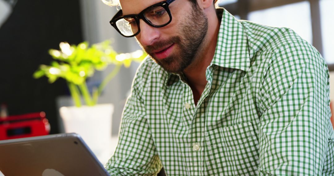 Young Man in Green Plaid Shirt Using Tablet at Home - Free Images, Stock Photos and Pictures on Pikwizard.com