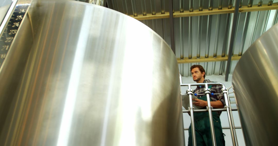 Brewery Worker Inspecting Large Fermentation Tanks - Free Images, Stock Photos and Pictures on Pikwizard.com