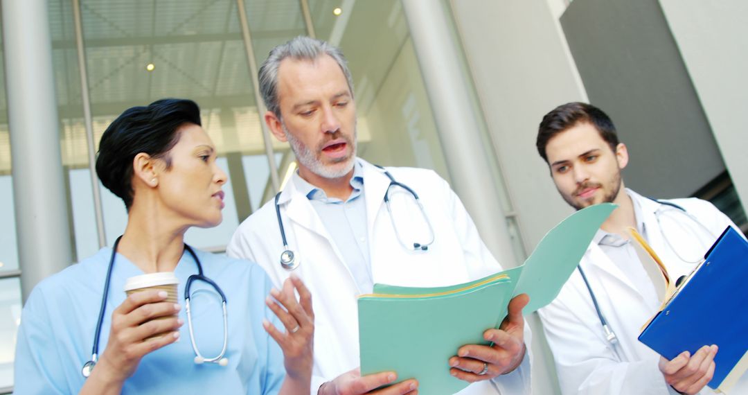 Medical Team Discussing Patient Charts Outside Hospital - Free Images, Stock Photos and Pictures on Pikwizard.com