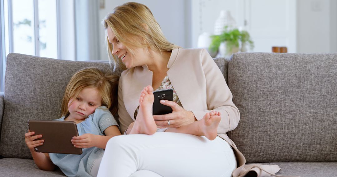 Mother and Daughter Relaxing on Couch Using Digital Devices - Free Images, Stock Photos and Pictures on Pikwizard.com