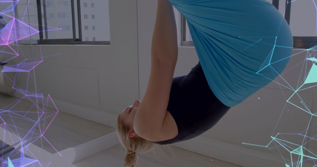 Aerial Yoga Enthusiast Holding Inverted Pose in Bright Studio