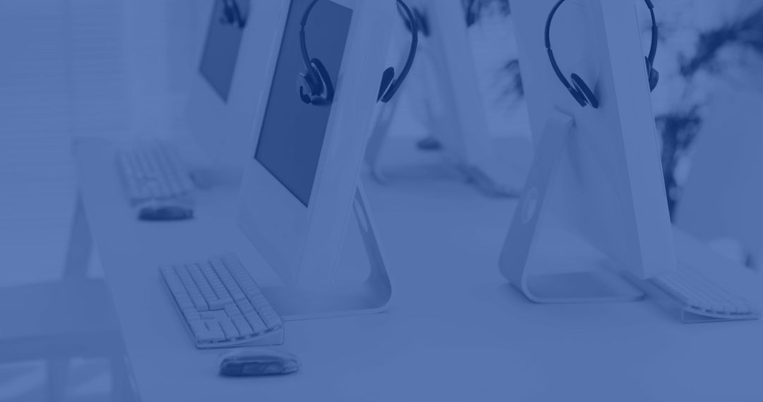 Row of Desktop Computers with Headsets in Office