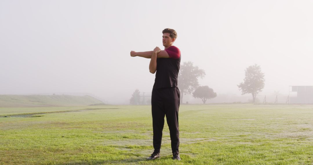 Athlete Stretching on Green Field at Dawn