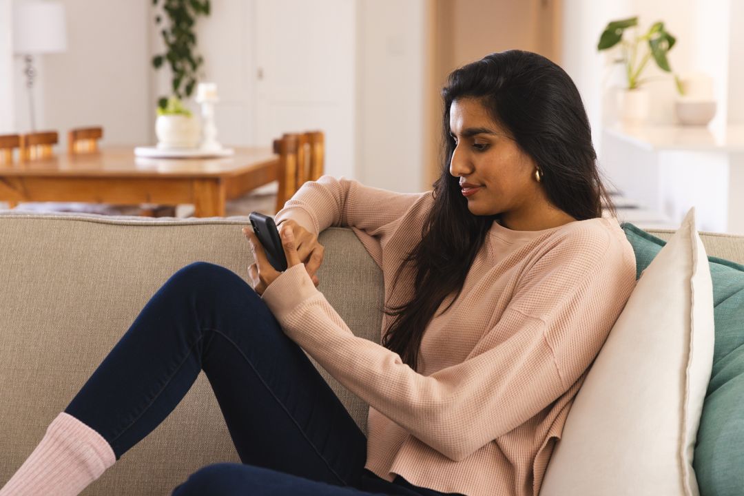Young Woman Relaxing Using Smartphone at Home on Comfortable Couch