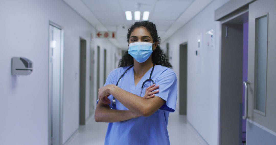 Portrait of asian female doctor wearing face mask and scrubs standing in hospital corridor - Free Images, Stock Photos and Pictures on Pikwizard.com
