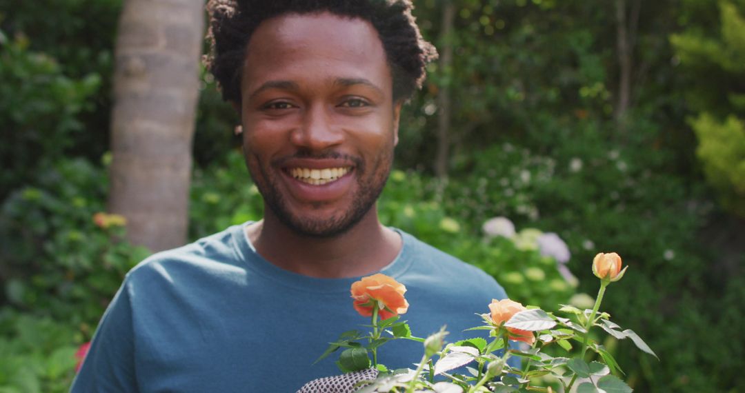 Smiling Biracial Man Enjoying Gardening in Blooming Garden