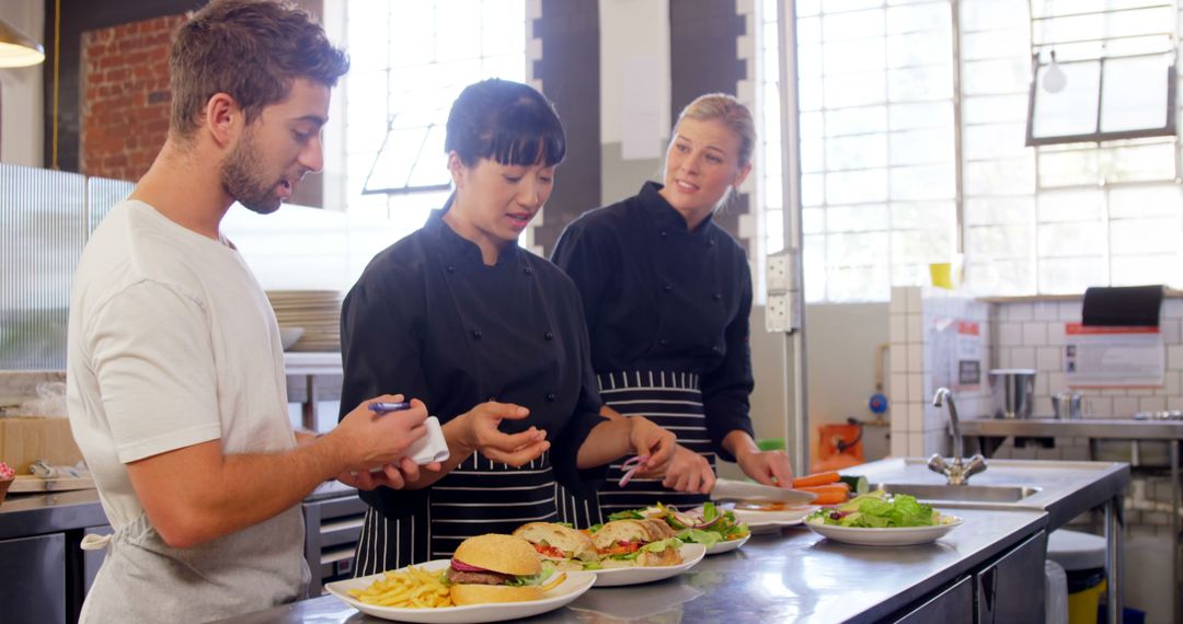 Chef Instructing Apprentices in Modern Industrial Kitchen - Free Images, Stock Photos and Pictures on Pikwizard.com