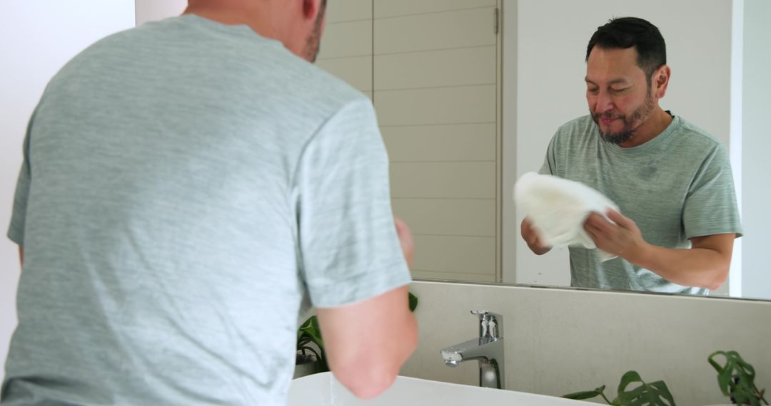 Mature Man Drying Face with Towel in Modern Bathroom