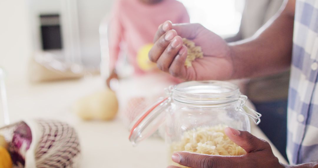 Close-up of Hands Holding Pasta Over Jar in Kitchen - Free Images, Stock Photos and Pictures on Pikwizard.com