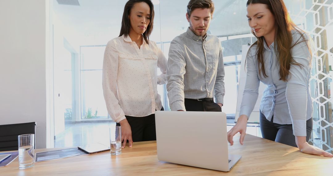 Collaborative Team Meeting Around Laptop in Modern Office