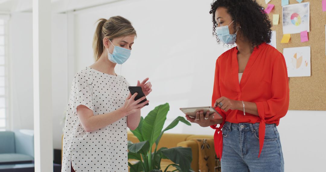 Two Businesswomen Collaborating While Wearing Face Masks in Office - Free Images, Stock Photos and Pictures on Pikwizard.com