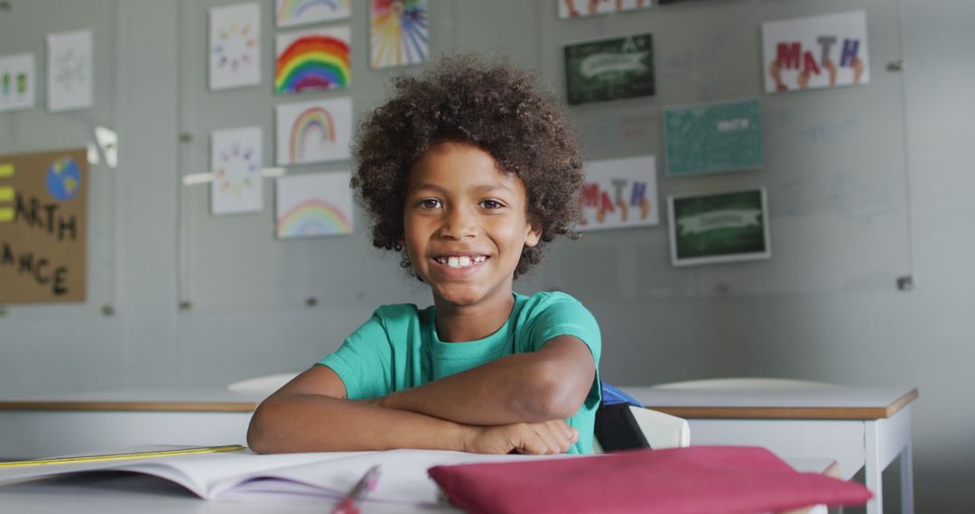 Image of happy biracial boy sitting at desk in classsroom - Free Images, Stock Photos and Pictures on Pikwizard.com