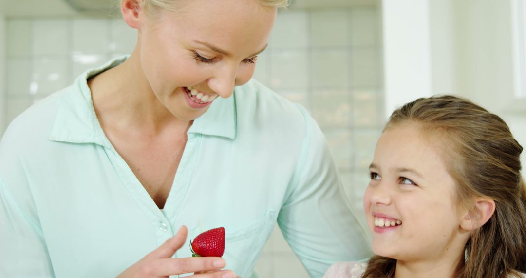 Smiling mother and daughter enjoying fresh strawberry in kitchen - Free Images, Stock Photos and Pictures on Pikwizard.com