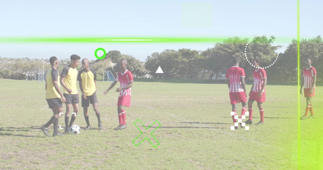 Standing around soccer ball, teammates discussing play on pitch with green graphic overlay
