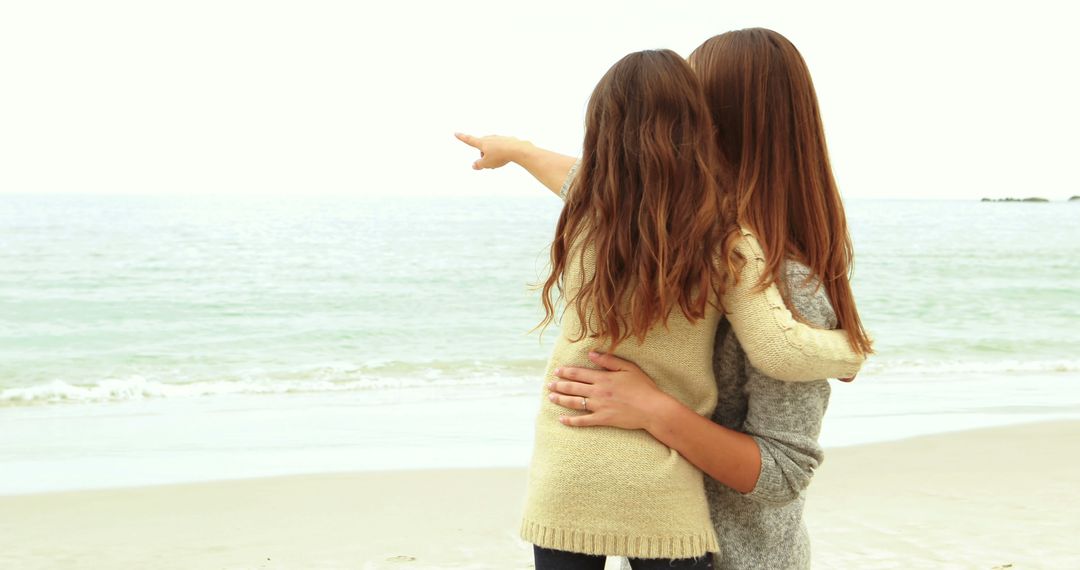 Women Hugging on Beach While Pointing at Sea - Free Images, Stock Photos and Pictures on Pikwizard.com