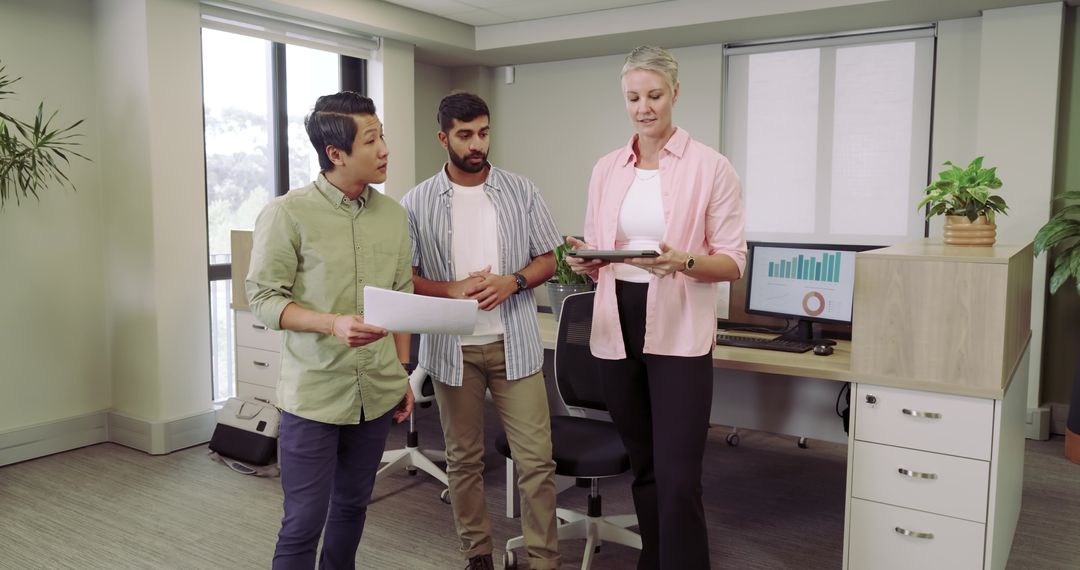 Diverse Team Collaborating in Modern Office with Tablet and Printout