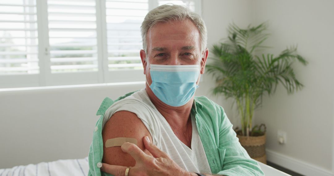 Senior Man Wearing Mask Showing Vaccination Bandage at Home - Free Images, Stock Photos and Pictures on Pikwizard.com