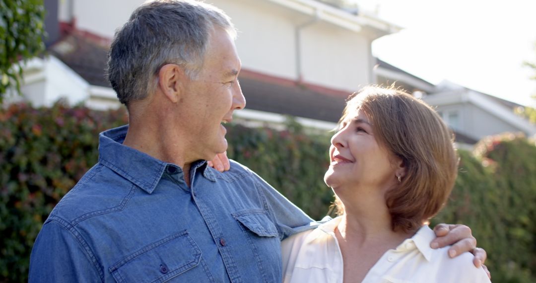 Senior Couple Embracing in Sunny Backyard Sharing Joyful Glances