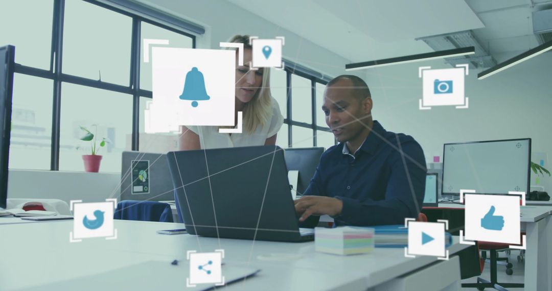 Two colleagues collaborating on laptop with social media icons overlay in modern office