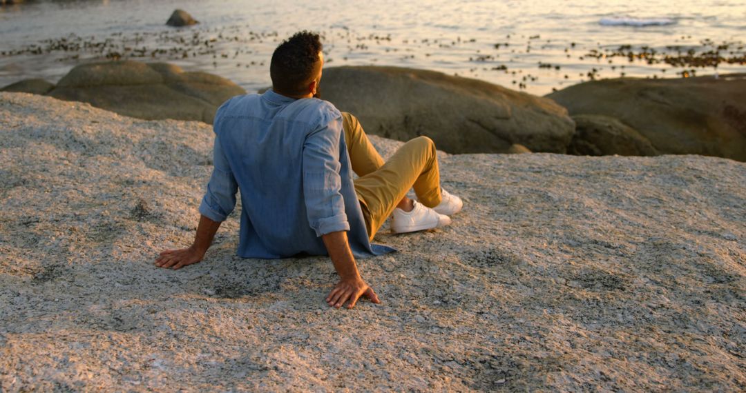 Man Relaxing on Rocky Beach During Sunset - Free Images, Stock Photos and Pictures on Pikwizard.com