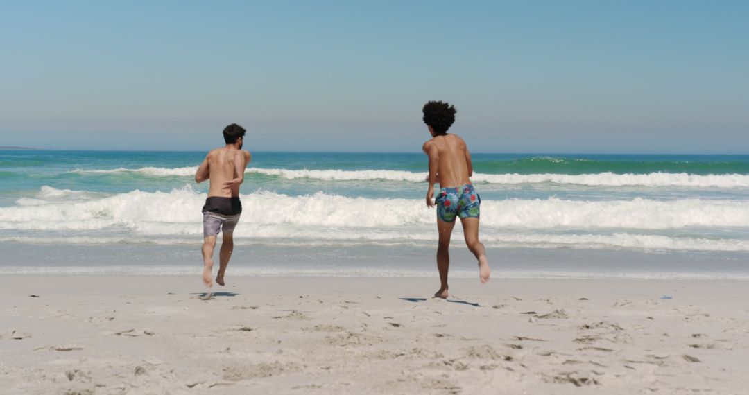 Two Young Men Running Towards Sea Waves on Beach - Free Images, Stock Photos and Pictures on Pikwizard.com