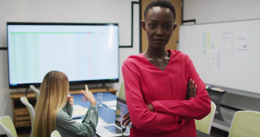 Confident project leader standing with arms crossed in modern office during data review