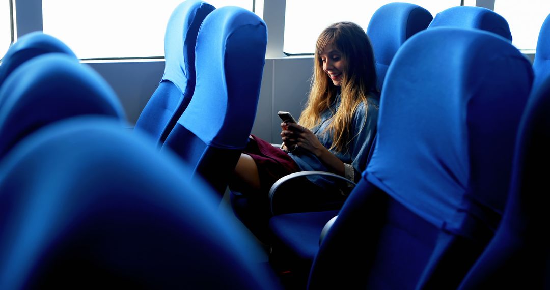 Woman Using Smartphone on Public Transport with Blue Seats - Free Images, Stock Photos and Pictures on Pikwizard.com