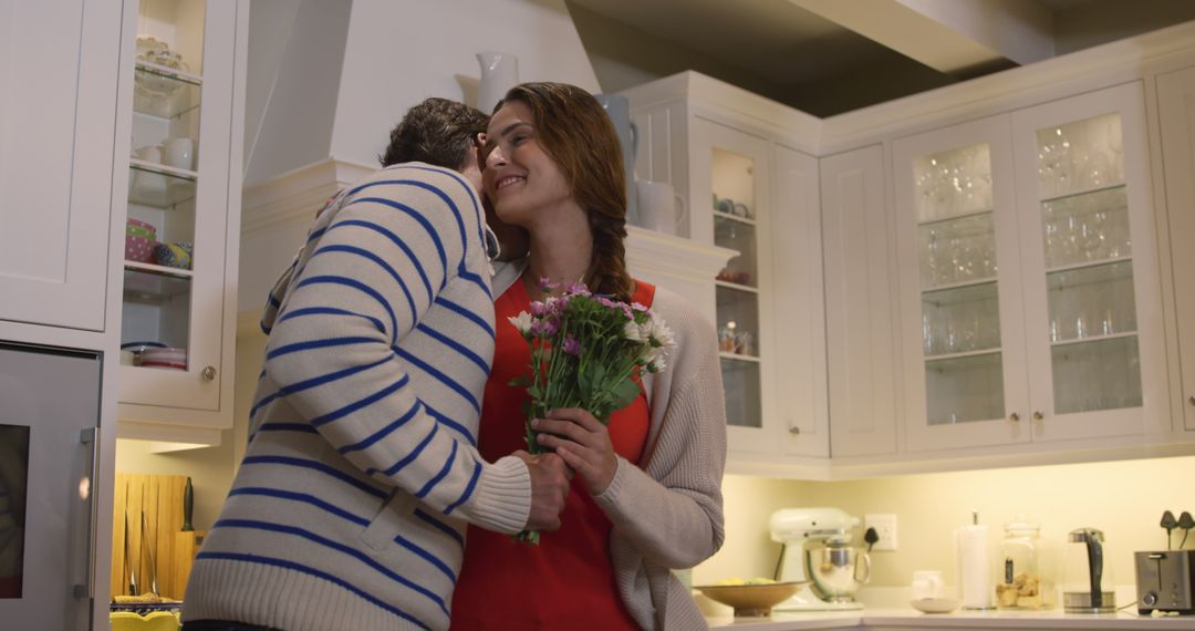 Joyful Couple Embracing with Flowers in Cozy Kitchen - Free Images, Stock Photos and Pictures on Pikwizard.com