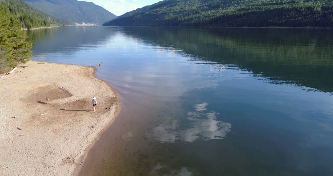 Solitary Hiker on Remote Sandy Beach by Serene Mountain Lake - Free Images, Stock Photos and Pictures on Pikwizard.com