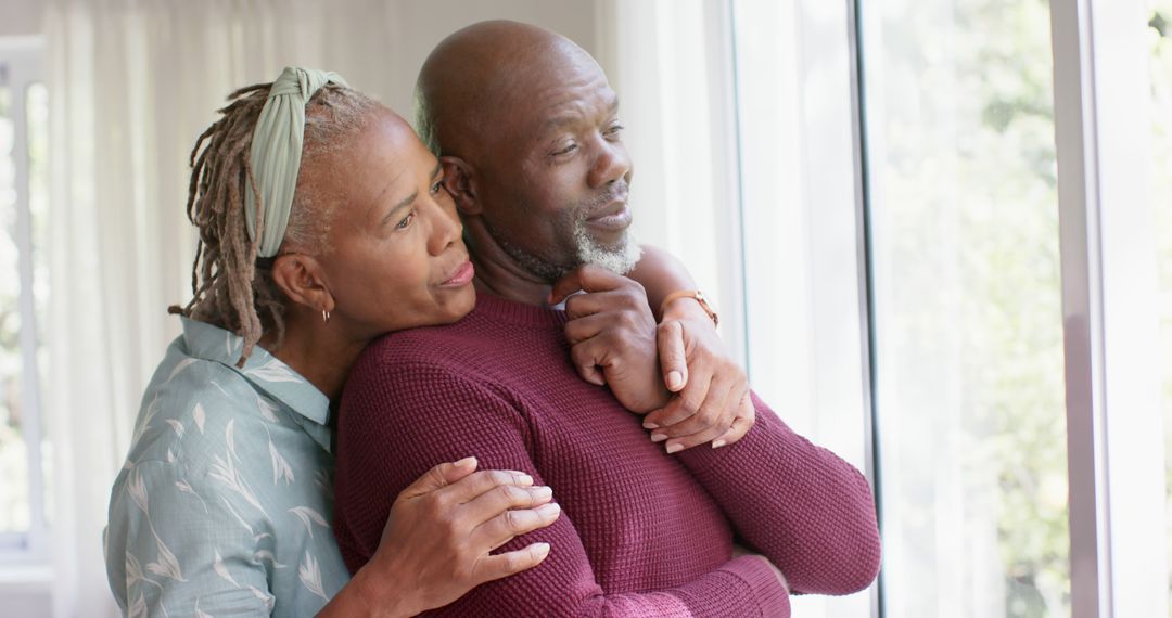 Loving Senior Couple Embracing and Looking Out Window